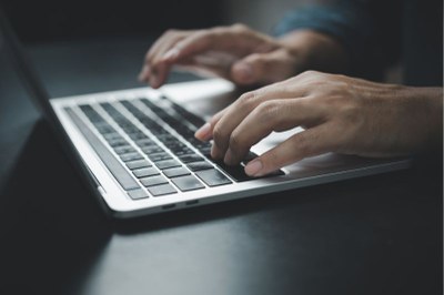 Imagem em detalhe de um homem digitando em um teclado de notebook