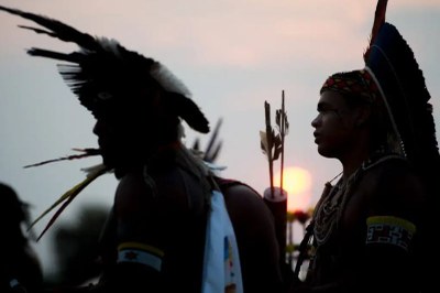 Imagem mostra silhueta de dois indígenas com cocares