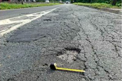 A imagem mostra trecho da BR-101 com asfalto cedendo, buracos e falta de manutenção básica. Perícia técnica do MPF utilizou instrumentos de medição para documentar a situação da rodovia