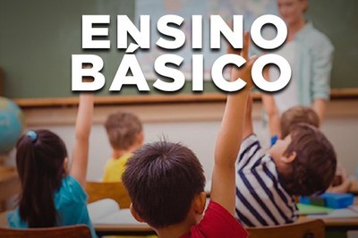 A imagem mostra uma sala de aula do ensino básico. Na parte superior, em letras grandes e brancas, está escrito “ENSINO BÁSICO”.

No primeiro plano, aparecem crianças sentadas em carteiras, vistas de costas. Algumas levantam a mão, como quando querem responder a uma pergunta ou participar da atividade. Elas estão em um ambiente típico de sala de aula: há materiais escolares sobre as mesas e um quadro ao fundo. Mais ao fundo, um(a) professor(a) está em pé diante da turma, próximo ao quadro, conduzindo a atividade. A cena transmite a ideia de participação, aprendizado e ambiente escolar infantil.
