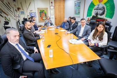 foto mostra 10 pessoas sentas ao redor de mesa de reunião