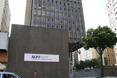 Foto mostra entrada prédio-sede da Procuradoria Regional da República da 3ª Região, uma edificação cinza com entrada envidraçada.